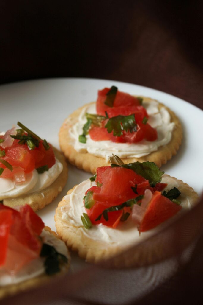 tartine tonde con mousse di tonno e pomodorini poste su un piatto da portata bianco