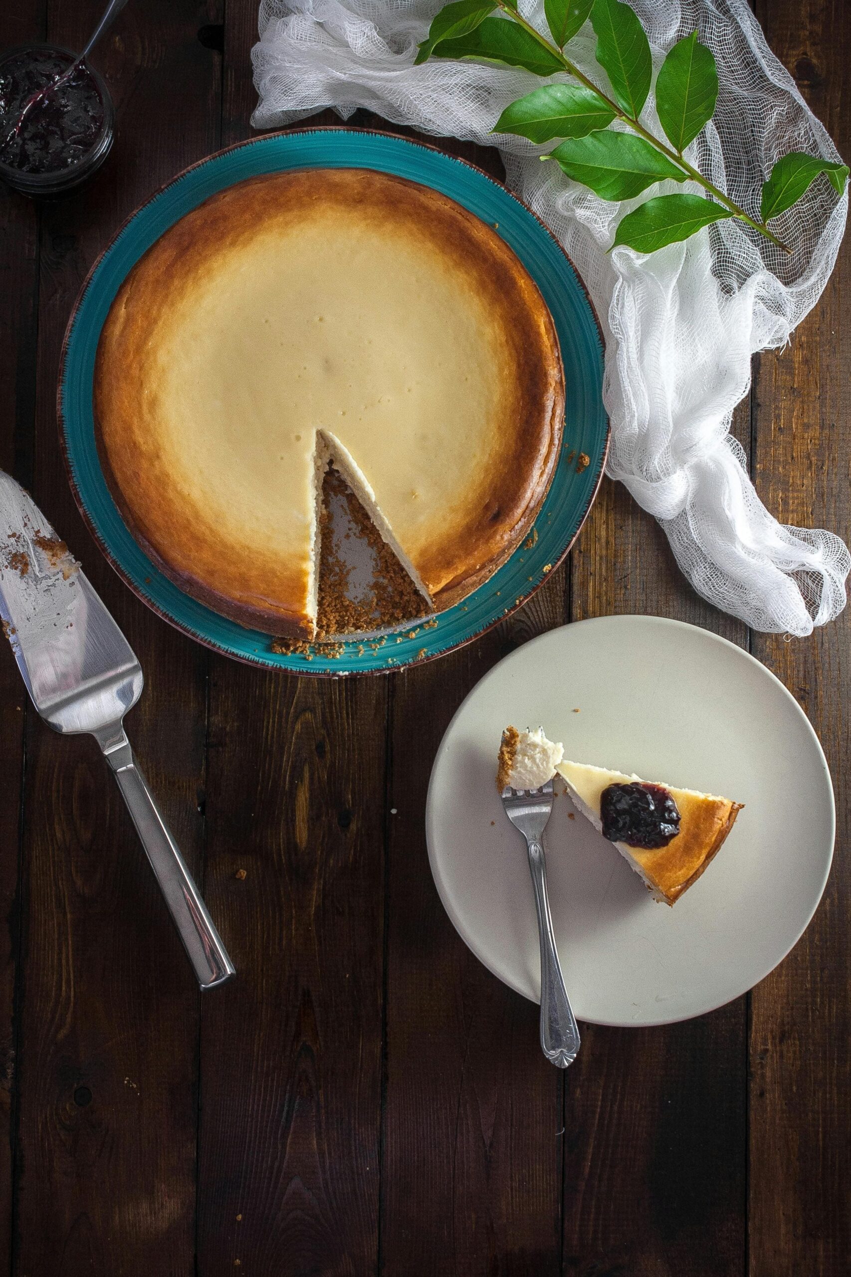 torta vista dall'alto a cui manca una fetta che è posta vicino su un piatto e guarnita con marmellata